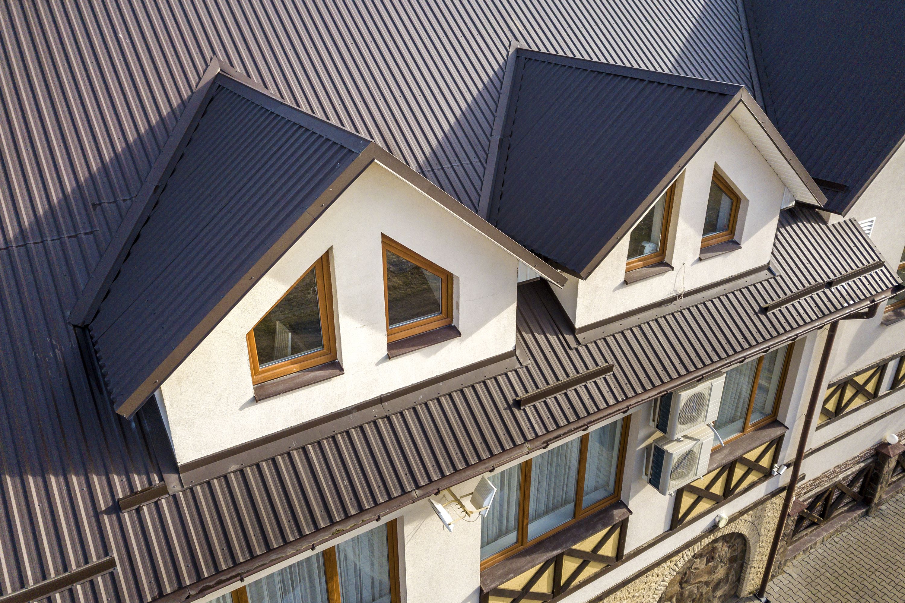close-up-aerial-view-of-building-attic-rooms-exterior-on-metal-shingle-roof--stucco-walls-and-plastic-windows--1145254175-0c436898f5574647812e891aa258bf3e